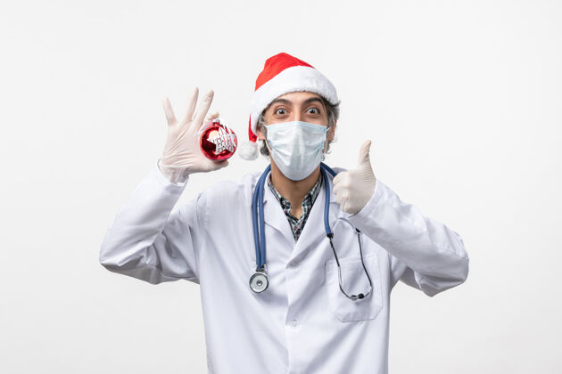 外套正面图白墙上戴着玩具面具的男医生健康病毒共度新年视图医药科维德