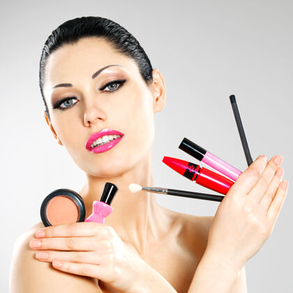 化妆品美丽的女人用化妆工具靠近她的脸套女人肖像