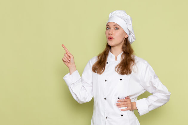 成人身着白色厨师服的女厨师在绿墙上摆姿势的正面图厨师人食物