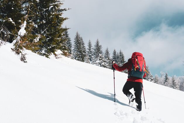 男性一个男性徒步旅行者带着一个红色的旅行背包在冬天登上雪山的美丽照片户外风景游客