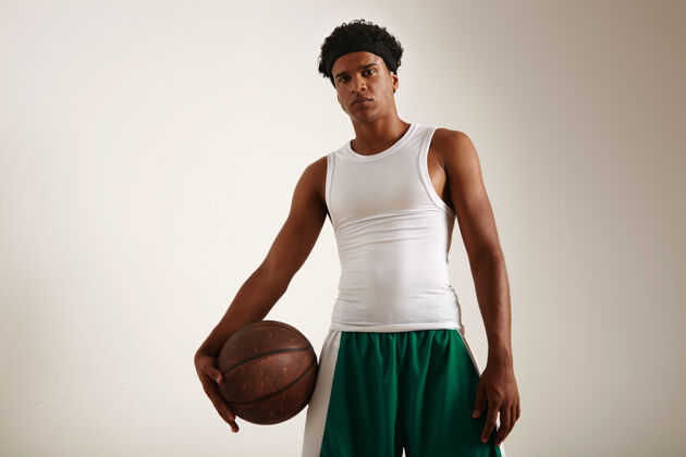 阳刚底图上的健美肌肉愤怒的非洲裔美国篮球运动员在白色和绿色制服举行一个垃圾篮球健身得分比赛