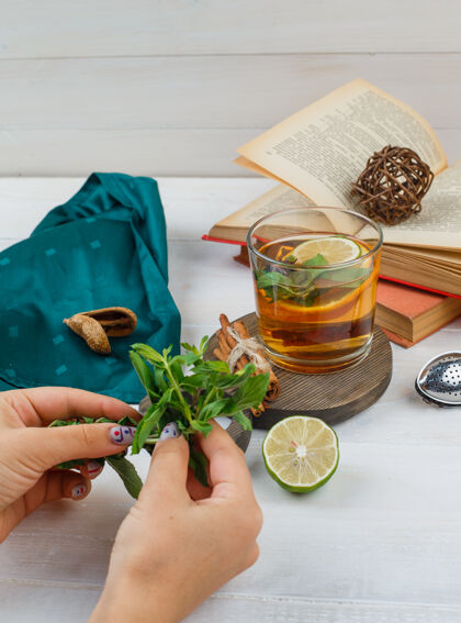 桌子一套书 柠檬 薄荷和绿领巾 凉茶和肉桂放在木板上书籍肉桂草药