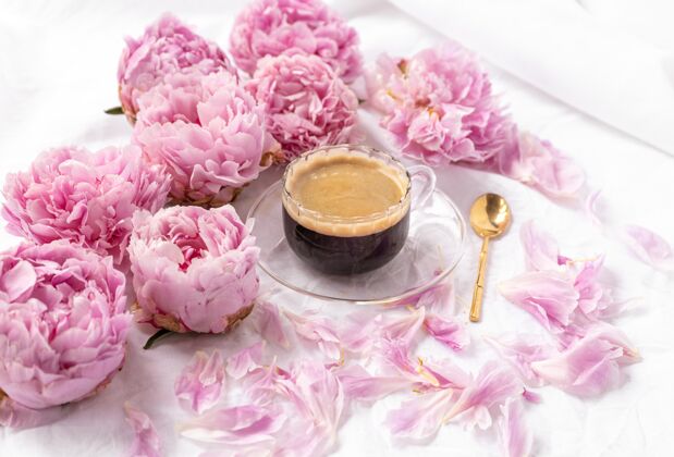 咖啡馆一杯速溶咖啡放在桌上的茶碟上的特写镜头 上面有粉色的牡丹花博客饮料热
