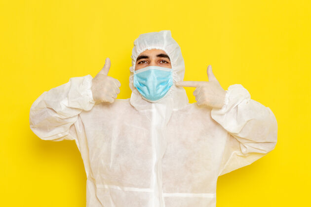 实验室身穿白色防护服 带面罩 浅黄色墙壁的男性科学工作者正面图科学医生危险