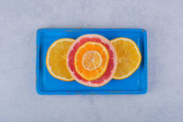 柠檬把新鲜的柚子 橙子和柠檬片放在蓝色盘子里葡萄柚成熟健康