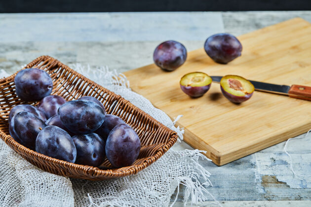 紫色成熟的全李子和半李子放在木板上浆果桌子木板