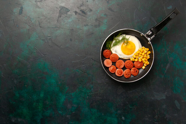 盘子俯瞰深绿色书桌上的炒鸡蛋 香肠和绿色蔬菜鸡蛋美味菜