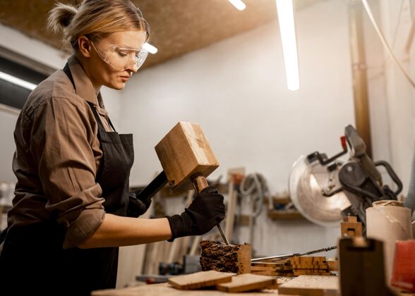 工人女木匠在工作室雕刻木头的侧视图职业工作劳动者