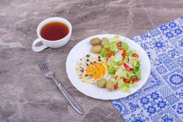 橄榄煎鸡蛋和切碎的青菜沙拉配一杯茶白新鲜食品
