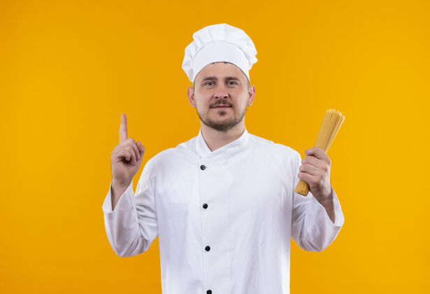 厨师穿着厨师制服的年轻帅哥厨师手拿意大利面 指着橙色的空间向上指着制服