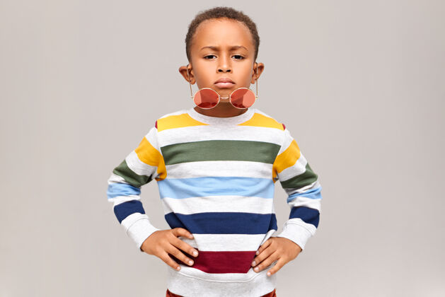 小酷帅的非洲裔美国孩子有自信的面部表情 双手放在腰上 时尚的圆形粉色阴影从鼻子上落下童年和时尚的概念年轻非洲肖像
