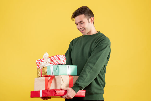 成人正面是穿着绿色毛衣拿着礼物站在黄色的快乐男人快乐毛衣微笑