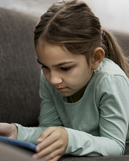 安全无聊的小女孩在家玩智能手机流行病住宿孩子