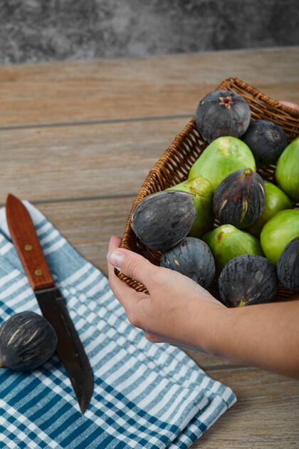 健康一只手拿着一篮子无花果放在木桌上 手里拿着刀和桌布手维生素桌布