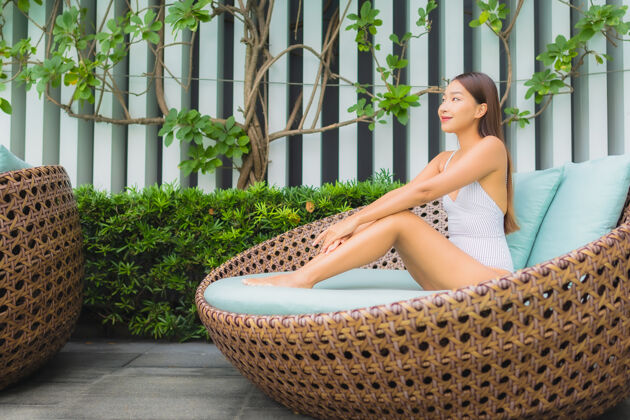 微笑肖像美丽的亚洲年轻女子在酒店度假区的室外游泳池周围放松休闲旅游度假度假胜地身体泳装