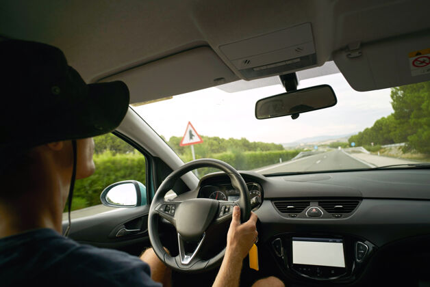 年轻司机开车在高速公路上行驶 从车内看风景手放在方向盘上 寒冷的夏天手水平天空