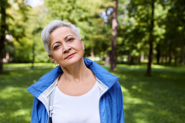 退休者快乐的白种老年女性肖像 灰色短发在公园里放松 表情平和或体贴 享受独处野外的时光 呼吸着新鲜的冷空气老年人放松成熟