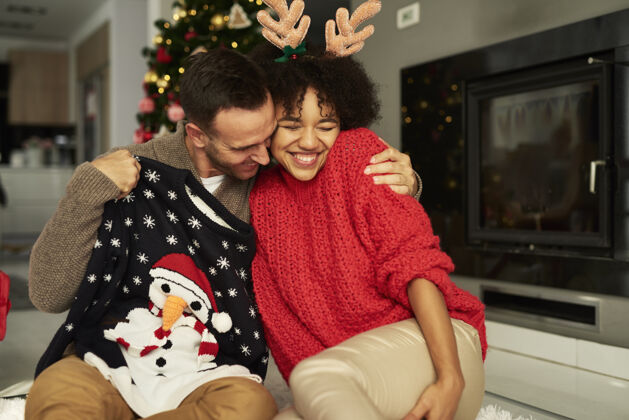 债券恩爱的情侣在圣诞节拥抱圣诞礼物家庭内部圣诞装饰