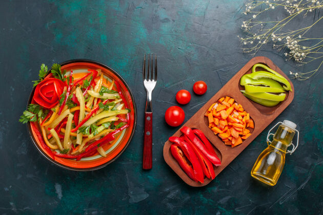油顶视图切片甜椒不同颜色的蔬菜沙拉与原料和油在深蓝色的背景健康蔬菜背景