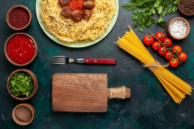 面团在深蓝色的背景上俯瞰美味的意大利面食和肉丸及调味品一餐肉面食