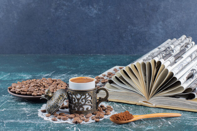 勺子一杯泡沫咖啡 一盘咖啡豆和一本大理石桌上的书美味香味磨碎的咖啡