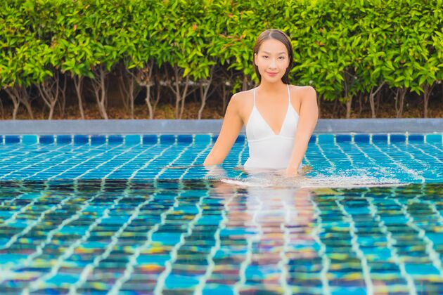泳装肖像美丽的亚洲年轻女子放松微笑休闲围绕室外游泳池近海乐趣放松晒黑