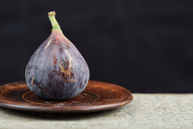 新鲜一个无花果放在小盘子和大理石桌上健康热带紫色