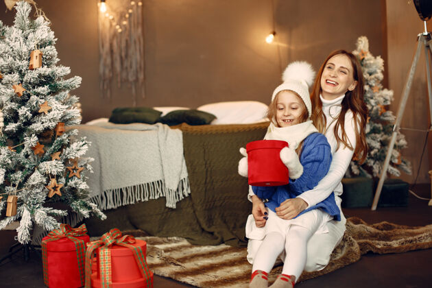 礼物人们在为圣诞节做准备母亲在和女儿玩耍一家人在节日的房间里休息孩子穿着蓝色毛衣发光装饰毛衣