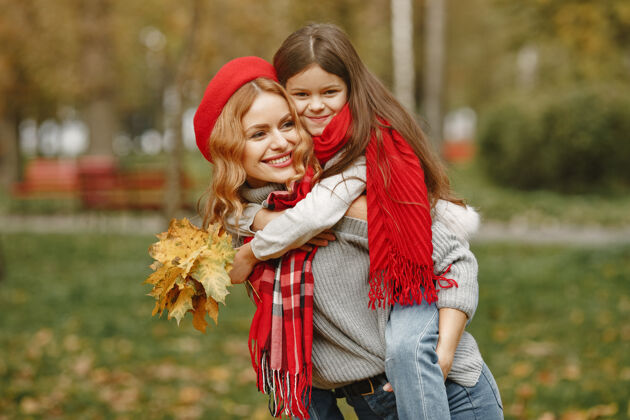 女孩时髦的母亲带着女儿黄色的秋天戴着红领巾的女人快乐衣服乐趣