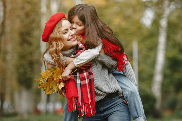 女性时髦的母亲带着女儿黄色的秋天戴着红领巾的女人蓝色快乐快乐