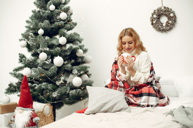 礼物房间里的女人穿白色毛衣的金发女人圣诞树旁的女人欧洲化妆品庆祝