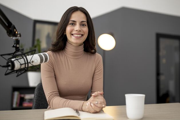 水平微笑的女人 拿着麦克风和咖啡在广播室里女人公告媒体