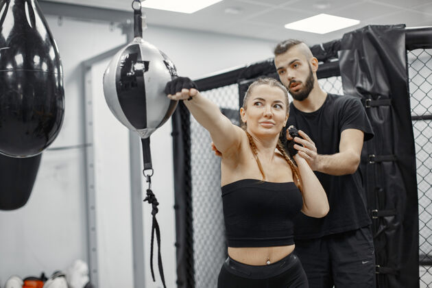 搏击女子拳击健身房的初学者穿黑色运动服的女士有教练的女士运动装拳击手拳击
