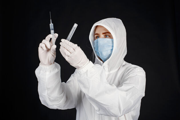 注射器戴着医用面罩的医生冠状病毒主题白色背景下隔离穿防护服的女人实验室肖像年轻