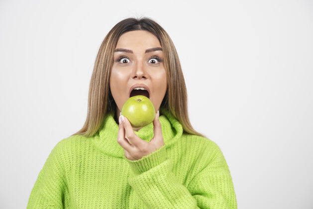 女人穿着绿色t恤的年轻女子正在吃苹果吃苹果水果