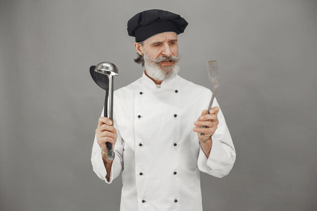 员工高级男子选择勺子厨师头上戴着一顶黑帽子工作工人员工