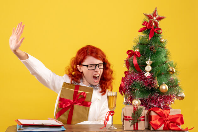 礼物前视图女医生坐在一个黄色的背景上与圣诞礼物情感人前面