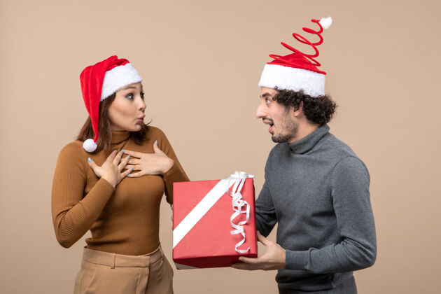 兴奋新年心情带着搞笑兴奋的可爱情侣戴着灰色的红色圣诞老人帽男性帽子圣诞老人