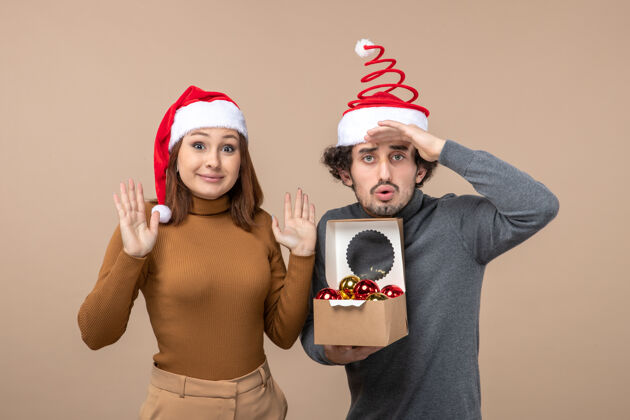 心情喜庆的心情与兴奋的酷情侣戴着红色圣诞老人帽的灰色股票形象衣服帽子圣诞老人