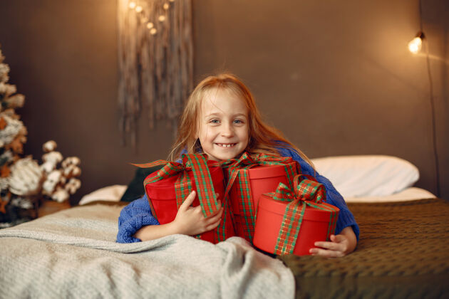 快乐穿蓝色毛衣的孩子坐在圣诞树旁的女儿坐节日玩具