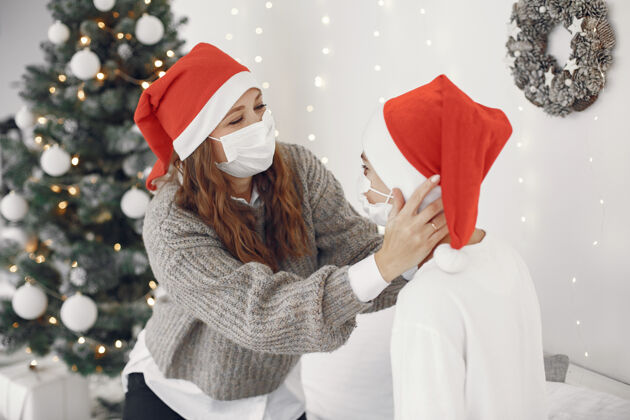 Covid19为圣诞节做准备的人冠状病毒主题妈妈和儿子玩穿白毛衣的男孩孩子十二月传统