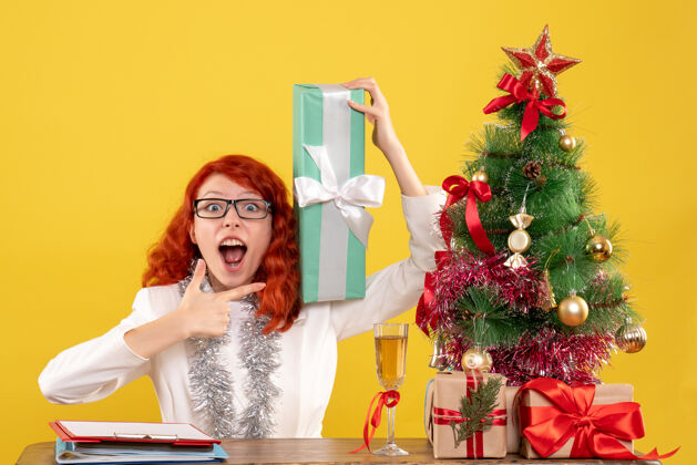 情感正面图：女医生拿着圣诞礼物坐在黄色的树上地板圣诞坐着