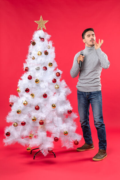 演讲新年气氛积极的家伙穿着牛仔裤站在装饰圣诞树附近心情圣诞树圣诞节