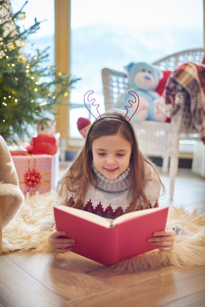 地板小女孩在地板上看书圣诞树欢乐阅读