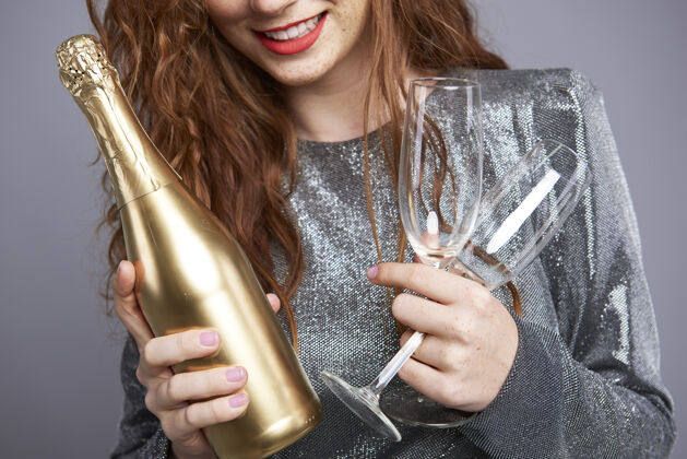 年手持香槟笛和香槟瓶的年轻女子举行女人周年纪念