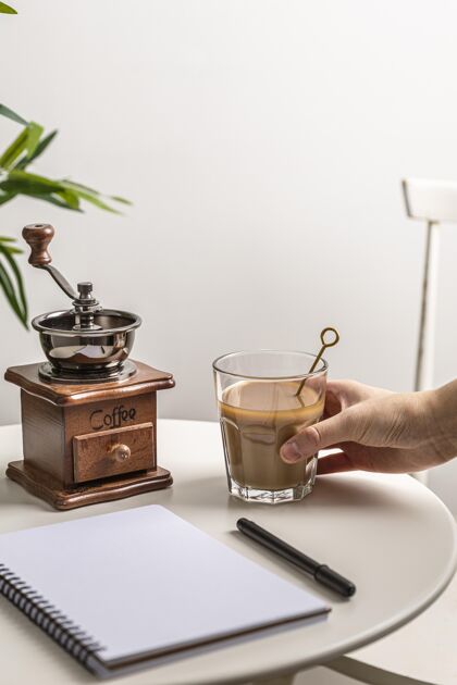 勺子高角度的咖啡杯与研磨机和笔记本放在桌上笔记本咖啡饮料