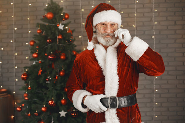 夜晚圣诞老人站在圣诞树旁家装欢乐手套帽子