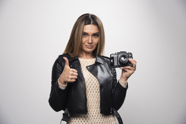姿势一位身穿黑色皮夹克的年轻女士 以积极微笑的态度 用相机拍照休闲人类自拍