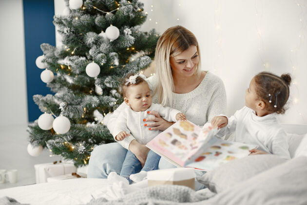 毛衣人们在为圣诞节做准备母亲在和女儿们玩耍一家人在节日的房间里休息孩子穿着毛衣小牛仔裤室内