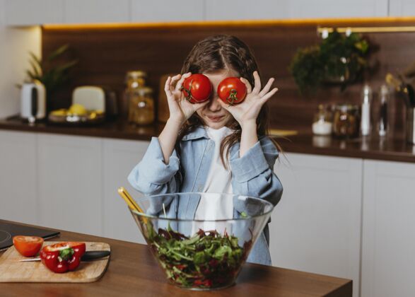 一起厨房里小女孩拿着西红柿的正视图蔬菜前面前面视图